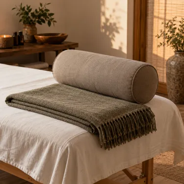A bolster and a folded blanket at the end of a massage table.